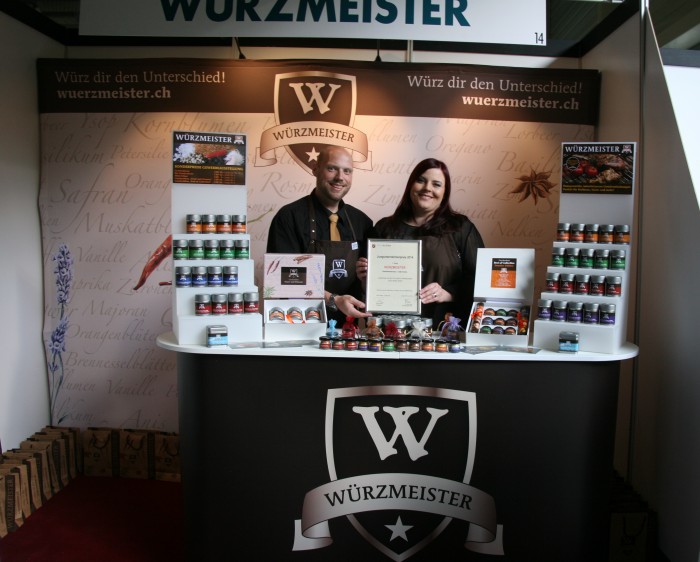 Bild zum Beitrag Würzmeister gewinnt den Jungunternehmerpreis Kloten 2014. Yves und Tania präsentieren den Preis hinter dem Stand.