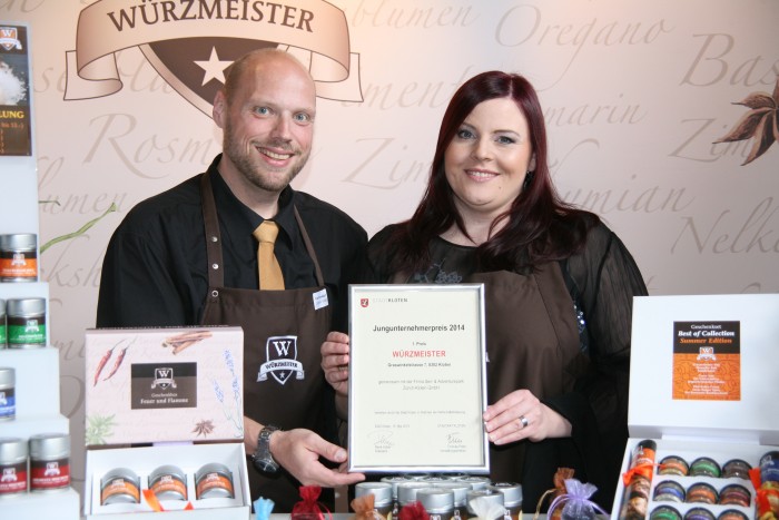 Bild zum Beitrag Würzmeister gewinnt den Jungunternehmerpreis Kloten 2014. Yves und Tania präsentieren den Preis hinter dem Stand.