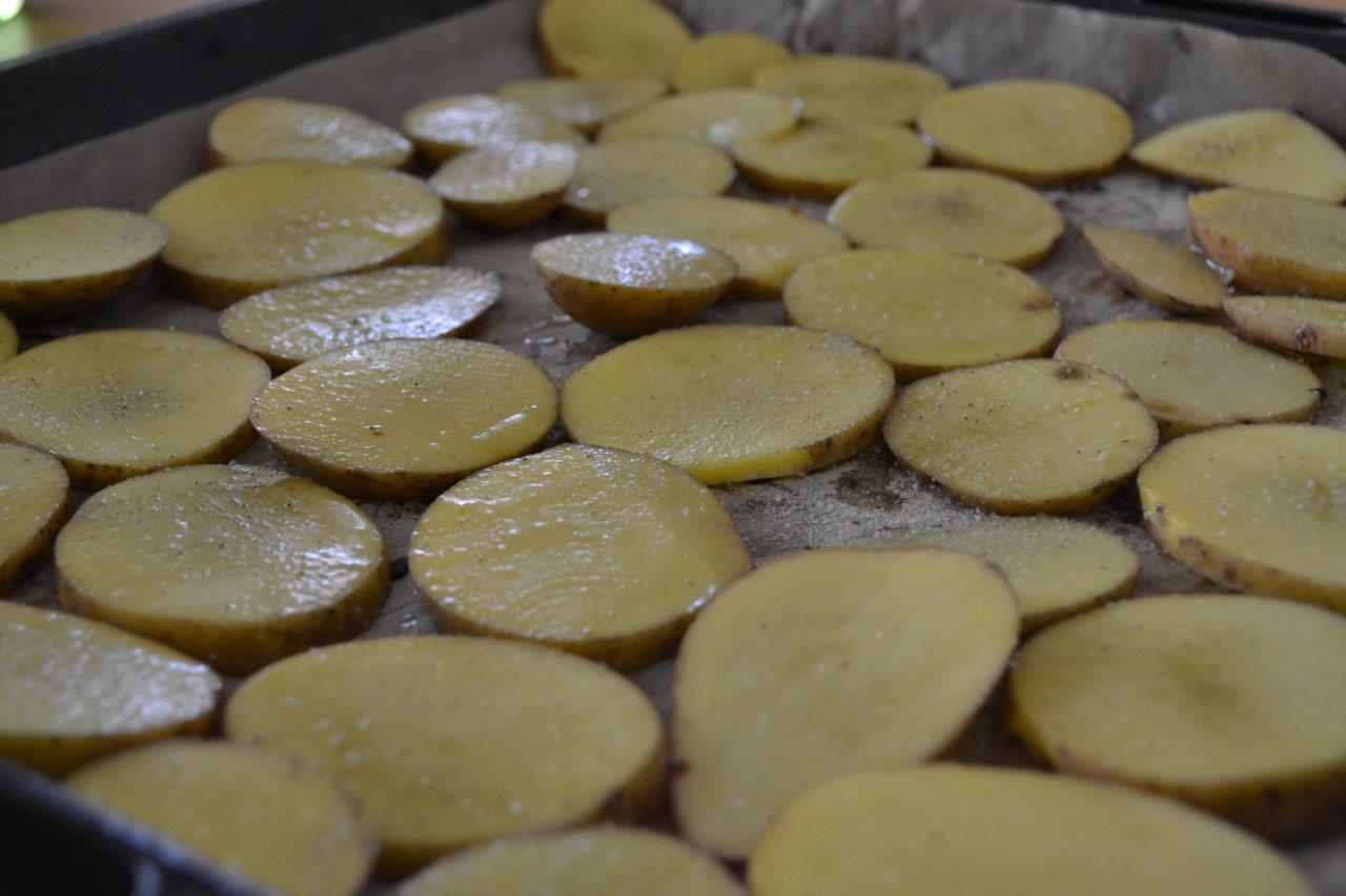 Bild zum Rezept Kartoffeln mit Rosmarin-Knoblauch Salz. Gesalzene und geschnittene Chips bereit für den Ofen.